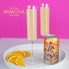 two champagne flutes and an orange slice on a plate