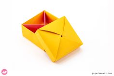 an origami box that is yellow and has a red paper in the middle