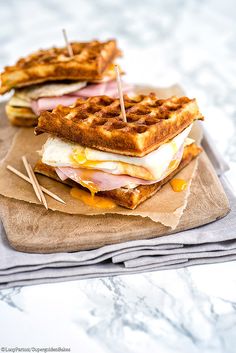 two waffle sandwiches with ham and cheese on them sitting on top of napkins