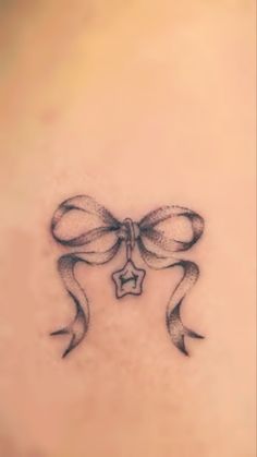 a bow tattoo on the back of a woman's upper arm, with a star in the middle