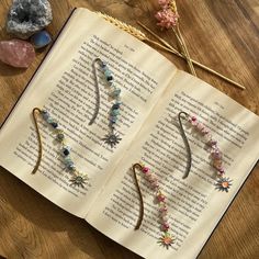 an open book sitting on top of a wooden table next to some rocks and flowers