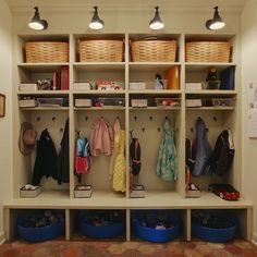 an organized mudroom with baskets and clothes