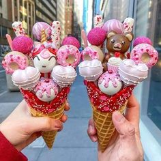 two people holding up ice cream cones with teddy bears on them and pink sprinkles