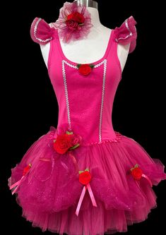 a pink dress with red roses on the bottom, and two bows at the waist