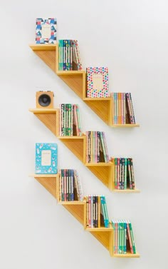 three wooden shelves with books on them and a camera in the corner next to each other