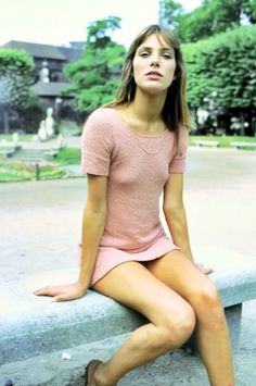 a woman sitting on top of a cement bench