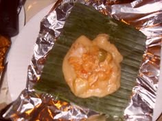 a piece of food is on top of tin foil and sits on a white plate