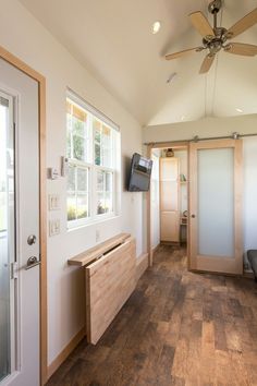 a living room with wood floors and ceiling fan in the corner next to sliding glass doors