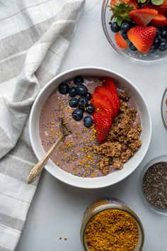 a bowl of oatmeal with strawberries, blueberries and granola