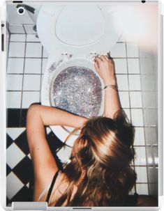 a woman sitting in front of a white toilet with glitter on the seat and lid