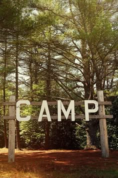 a wooden sign that says camp in front of some trees