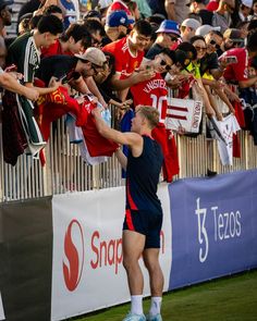 a tennis player is reaching for the ball in front of a large group of fans