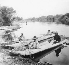 an old black and white photo of some people in a canoe