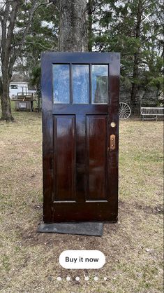 a wooden door sitting in the grass next to a sign that says buy it now