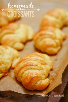 freshly baked croissants are lined up on a piece of waxed paper