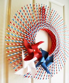 two red, white and blue pinwheels are hanging on the front door wreath