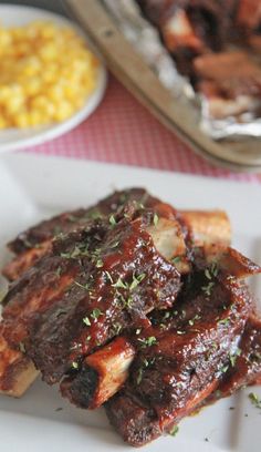 a plate with ribs, corn and barbecue sauce on it