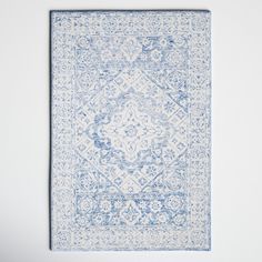 a blue and white area rug with an intricate design in the middle, against a white wall