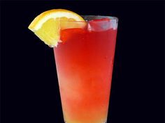 a tall glass filled with red liquid and a lemon slice