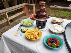 a table topped with plates and bowls filled with food next to an ice cream fountain