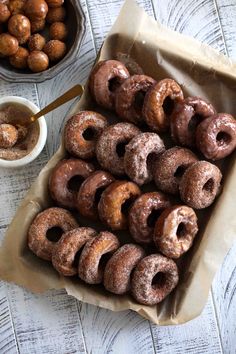 there are many donuts on the table with dipping sauces and nuts in bowls