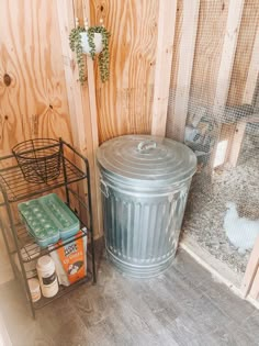 a metal trash can sitting next to a chicken coop