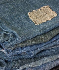 several pieces of blue jeans are stacked on top of each other, with one patch in the middle