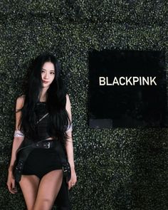 a woman with long black hair standing in front of a sign that says blackpink