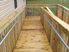 a wooden deck with metal handrails next to a house