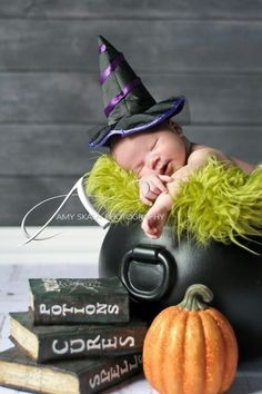 a baby sleeping in a witches hat on top of a pot with books next to it