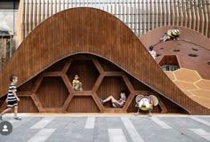 two children are sitting on benches in front of a wooden structure that has hexagonal structures