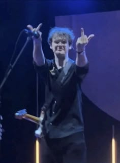 a man standing on top of a stage holding his hands up in the air while singing into a microphone