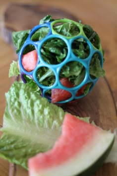 a watermelon and lettuce salad on a cutting board with a blue plastic ball