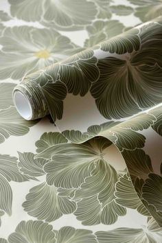 the wallpaper is green and white with large leaves on it's side, as well as a roll of tape