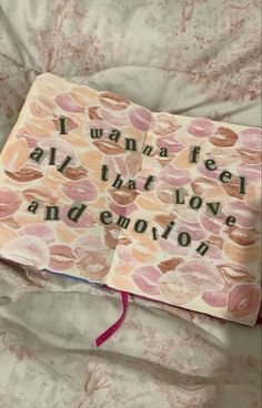 an open book laying on top of a bed covered in pink and white sheets with writing