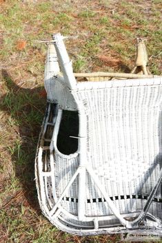 a white wicker chair sitting on top of a grass covered field next to a bottle opener