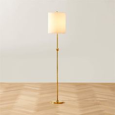 a floor lamp with a white shade on the top and a wooden floor below it