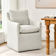 a white chair sitting next to a wooden table with a book on top of it