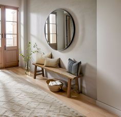 a wooden bench sitting in front of a mirror on the wall next to a door