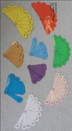 several different colored butterfly shaped tags on a white table cloth with numbers in the middle