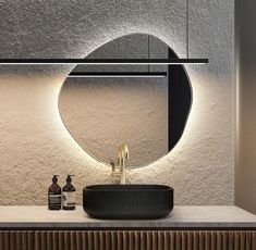 a bathroom with a sink, mirror and bottles on the counter top in front of it