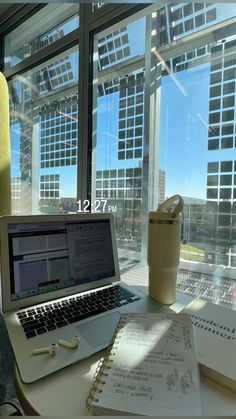 an open laptop computer sitting on top of a desk next to a cup and pen