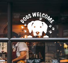 a dog's welcome sign in the window of a bakery