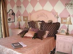 a bedroom with pink and white wallpaper has a bed, nightstands, and lamps