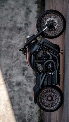 a black motorcycle parked on the side of a road next to a cement wall and sidewalk