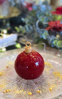 a red apple sitting on top of a glass plate covered in yellow sprinkles