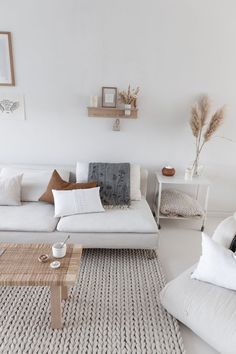 a living room filled with furniture and decor on top of a white floor covered in grey rugs