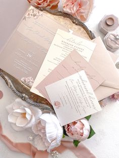 the wedding stationery is laid out on top of the table with pink and white flowers