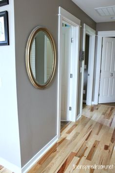 a room with wood floors and a mirror on the wall next to a white door