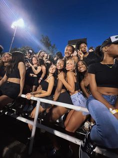 a group of young women sitting next to each other on bleachers at night